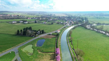 Vue aérienne sur le village de Champvert avec le canal et des arbres en fleurs rose