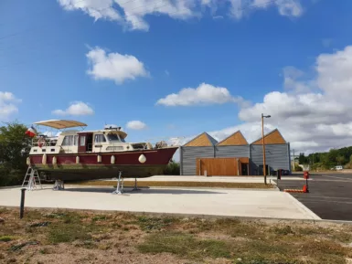 En arrière le plan, le Centre Technique Fluvial de Champvert et au premier plan un bateau en attente de réparation