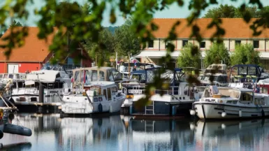 Vue depuis la dique sur les bateaux amarrés au Port de la Jonction de Decize avec la capitainerie et le restaurant au fond.