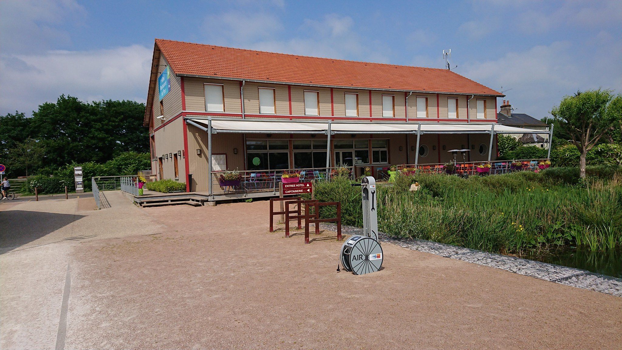 Vue sur le restaurant du port de Decize avec la terrasse donnant sur les bateaux et des services vélos (stations de réparation et gonflage vélos, racks)