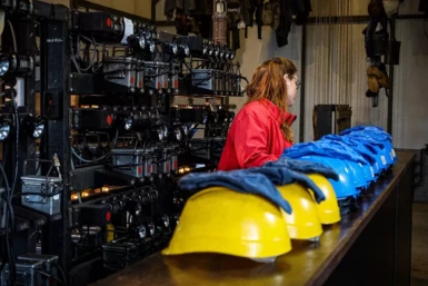 Le guide préparant casques et lampes dans la lampisterie en vue de la visite guidée